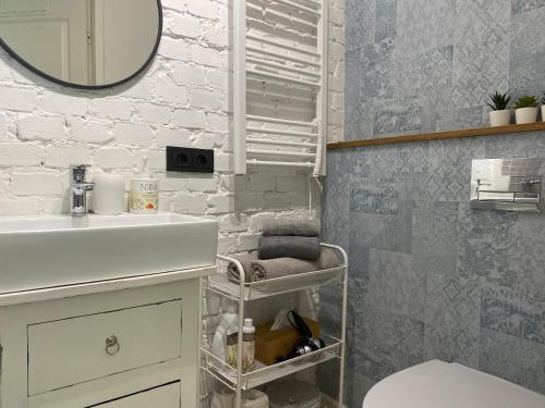 ein Badezimmer mit einem weißen Waschbecken und einem Spiegel in der Unterkunft Cozy and bright Šaulių studio in Klaipeda in Klaipėda