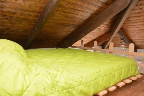 a green bed in a room with a wooden ceiling at Villa Gioia in Acqui Terme