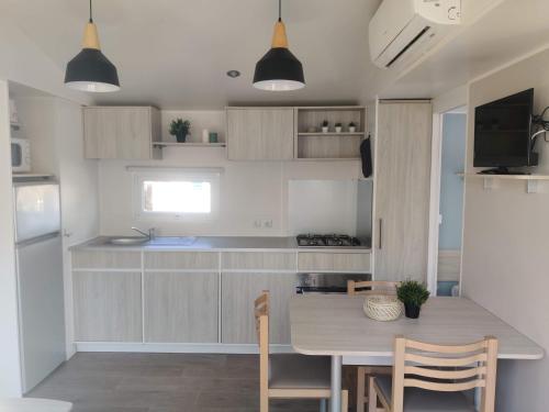 - une cuisine avec une table, des chaises et un comptoir dans l'établissement Mobil Home 6/8 personnes Camping le lac des rêves, à Lattes