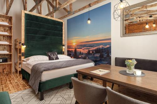a bedroom with a bed with a green headboard and a table at Mumlava Resort Harrachov in Harrachov