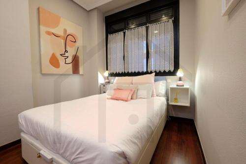 Schlafzimmer mit einem großen weißen Bett und einem Fenster in der Unterkunft La casa de Begoña - a un paso del centro de Gijón. in Gijón