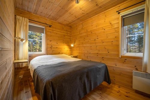 Cama en habitación de madera con 2 ventanas en Gezellige woning met hottub en sauna en Vradal