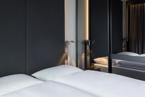 two white beds in a room with a mirror at Hotel AMANO East Side in Berlin