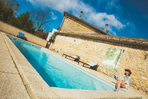 une femme assise sur une chaise à côté d'une piscine dans l'établissement Camping et Lodges de Coucouzac, à Lagorce