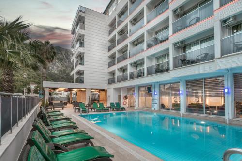 an image of a hotel swimming pool with chaise lounge chairs at Arbatt Marmaris Hotel in Marmaris