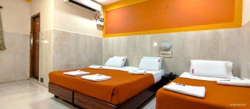 two beds in a room with orange sheets and towels at Sarovara Deluxe Rooms in Chennai