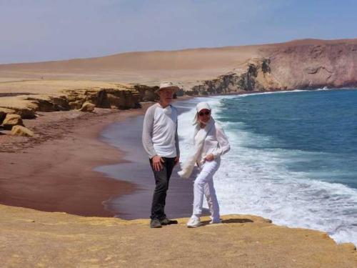 Un uomo e una donna in piedi sulla spiaggia di HOTEL LUCERO PARACAS a Paracas