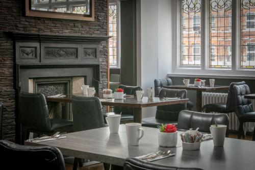 a restaurant with tables and chairs and a fireplace at The Crown London, WorldHotels Distinctive in London