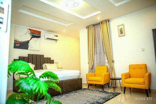 Habitación de hotel con 1 cama y 2 sillas de color naranja en House 475 Apartments. en Abuja