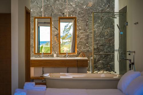 La salle de bains est pourvue d'une baignoire, d'un lavabo et de deux miroirs. dans l'établissement Beach Penthouse BELMARE, à Belle Mare