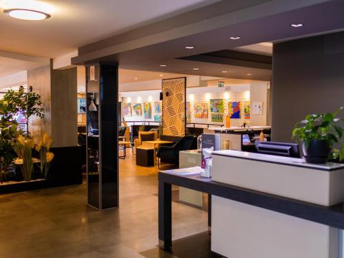 a lobby of a restaurant with tables and chairs at Mercure Lorient Centre in Lorient