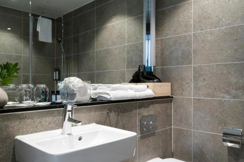 a bathroom with a sink and a tiled wall at The Wood Hotel by Elite in Skellefteå