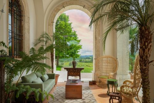 a living room with palm trees and a couch at Precise Tale Poggio Alla Sala in Montepulciano