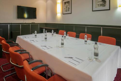 a conference room with a white table and orange chairs at The Crown London, WorldHotels Distinctive in London