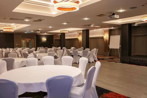 a conference room with white tables and chairs and a screen at The Crown London, WorldHotels Distinctive in London