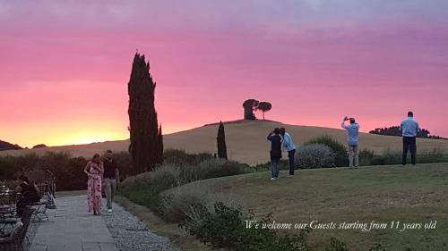 Un groupe de personnes debout sur une colline au coucher du soleil dans l'établissement Relais Sant'Elena, à Bibbona