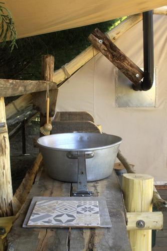 une grande baignoire en métal posée sur une table dans l'établissement Tente Trappeur Ada, Au jardin de la Vouivre, à Saint-Vincent-en-Bresse