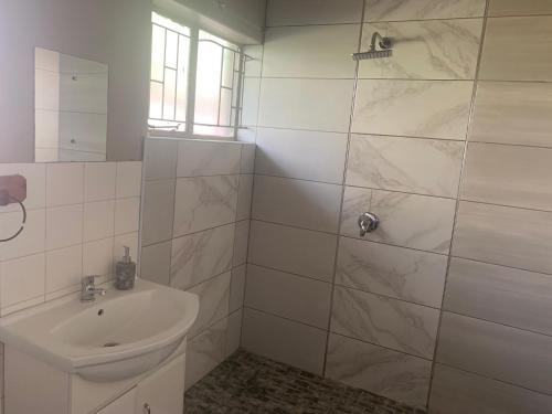 a white bathroom with a sink and a shower at Victoria guest house Nyumbani in Tzaneen
