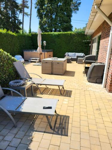 a patio with chairs and tables and a umbrella at villa 2be in Balen