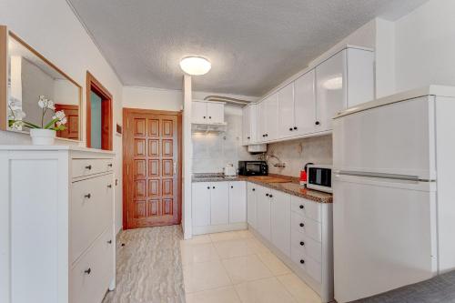 una cucina bianca con armadi bianchi e frigorifero di Torres del Sol Beach Front Apartment PH06 a Los Cristianos