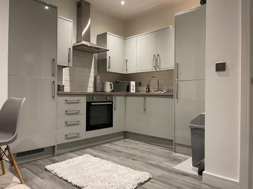 uma cozinha com armários brancos, uma mesa e um tapete em Augustus House 1 Bedroom Apollo Suite em Bradford
