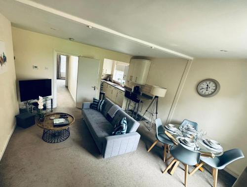 a living room with a couch and a table and a clock at Koala & Tree - Cozy and Centric 1 bed apartment - Short Lets & Serviced Accommodation Cambridge in Cambridge