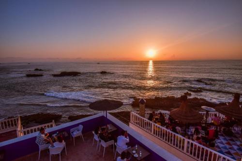 a group of people sitting at a restaurant on the beach at sunset at Palais Des Remparts in Essaouira
