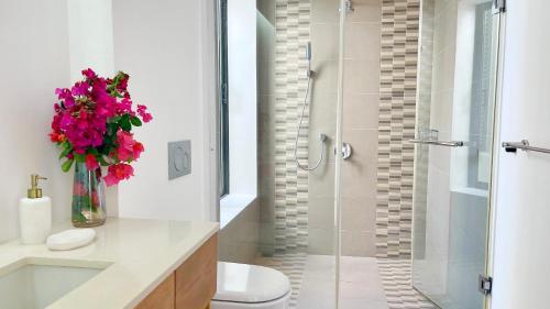 a bathroom with a shower and a vase of flowers at Beach Penthouse BELMARE in Belle Mare