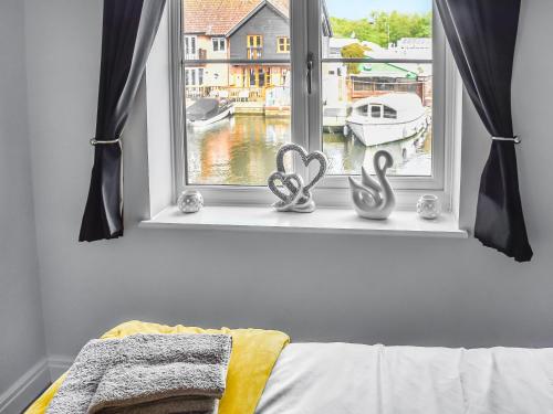een raam met 2 hartdecoraties in een slaapkamer bij Lilys Cottage in Wroxham