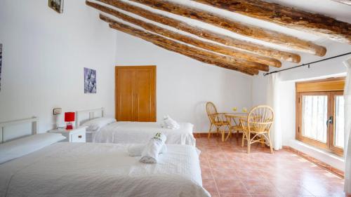 a bedroom with two beds and a table with chairs at Cortijo El Álamo 1 Vélez Blanco by Ruralidays in Vélez Blanco