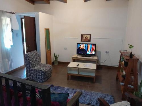 uma sala de estar com uma televisão e uma cadeira em La casa de MaCa em Posadas