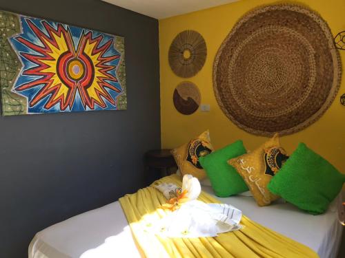 a bedroom with a bed with colorful pillows and a painting at Pousada Alto Astral in Olinda