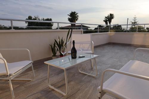 a table and chairs on a balcony with a bottle of wine at SUNSEA - Enjoy Your Family in Capo Vaticano