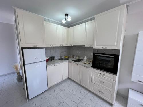 a white kitchen with white cabinets and a refrigerator at Stan na dan Sunce in Sremska Kamenica