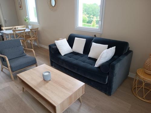 a living room with a black couch and a coffee table at Appartement Détente au Cœur du Cotentin in Valognes
