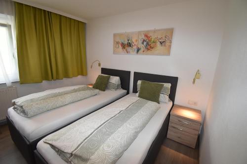 two beds in a room with green curtains at Hotel Martina in Telfs