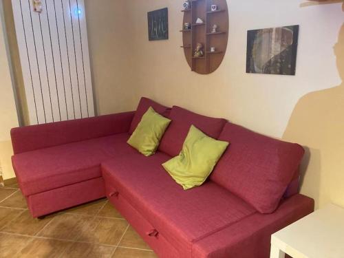 a red couch with yellow pillows in a living room at Grazioso appartamento tra Roma e il mare in Rome