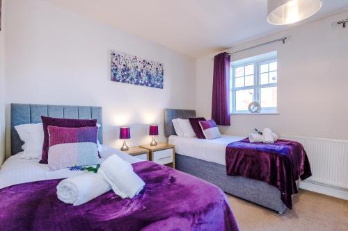 een slaapkamer met 2 bedden met paarse lakens en een raam bij Spacious 4-Bed Townhouse in Crewe by 53 Degrees Property, Ideal for Contractors & Business, FREE Parking - Sleeps 8 in Crewe