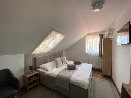 a bedroom with a bed with a window and a chair at Riviéra Apartmanok in Abádszalók