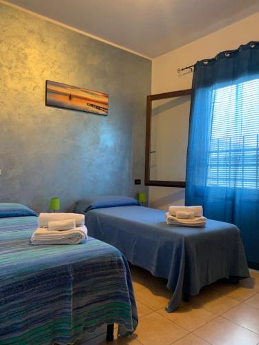 Santa Maria in PuntaにあるLa punta Rooms - Delta of the Po - Private Parkingのベッドルーム1室(ベッド2台、青いカーテン付きの窓付)