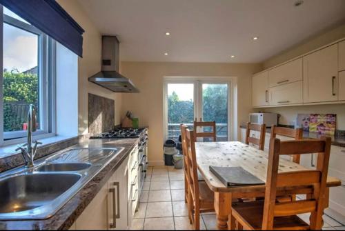 a kitchen with a sink and a table with chairs at Devonshire -Sleeps 19 in 7 ensuite bedrooms great space for all groups in Peak Forest