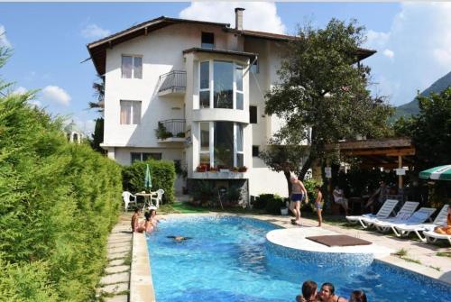 un grupo de personas en una piscina frente a una casa en Семеен Хотел Вит, en Teteven