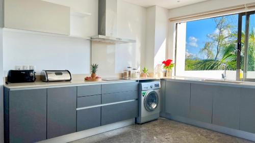 a kitchen with a washing machine and a window at Beach Penthouse BELMARE in Belle Mare