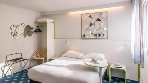 a room with two beds and a table at ibis Styles Fougeres in Beaucé