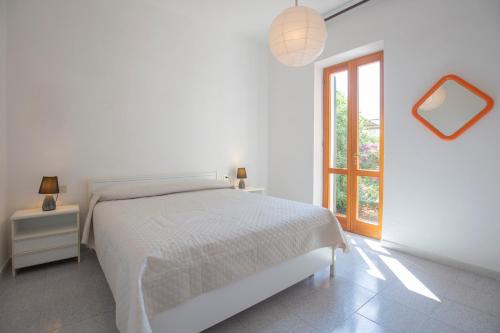 a white bedroom with a bed and a window at Casa Fetovaia - HelloElba in Fetovaia