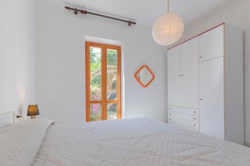 a white bedroom with a white bed and a window at Casa Fetovaia - HelloElba in Fetovaia