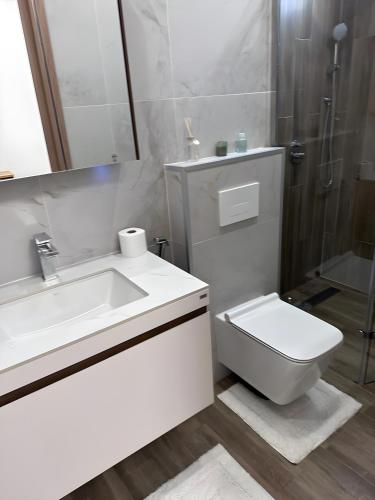 a white bathroom with a sink and a toilet at Studio Haut standing de dernière génération in Dakar