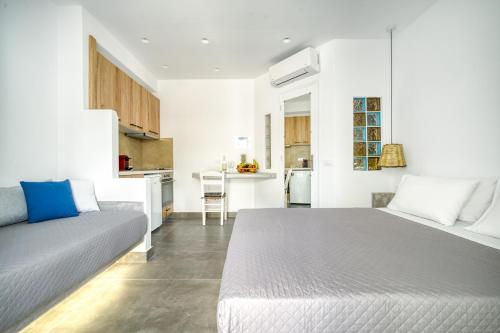 a white bedroom with a bed and a kitchen at Anius Apartments in Mýkonos City