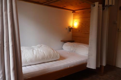 Solfé Backpacker في لوز سانت سوفير: سرير بشرشف ووسائد بيضاء في الغرفة