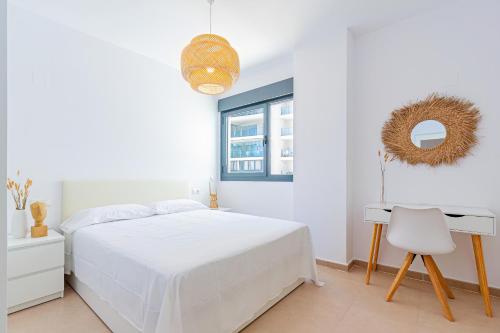 um quarto branco com uma cama, uma secretária e uma janela em CALA ALTA sunny apartment em Benidorm